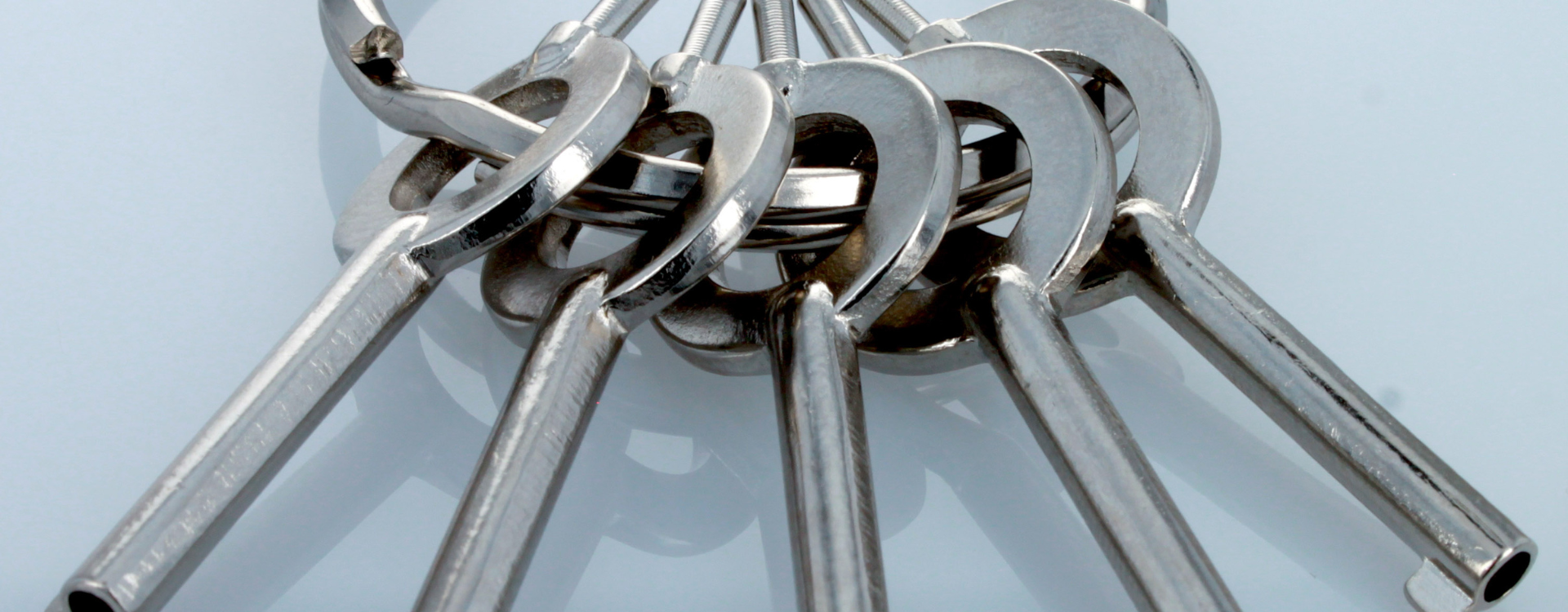 Set of metal handcuff keys on a light blue background on key ring