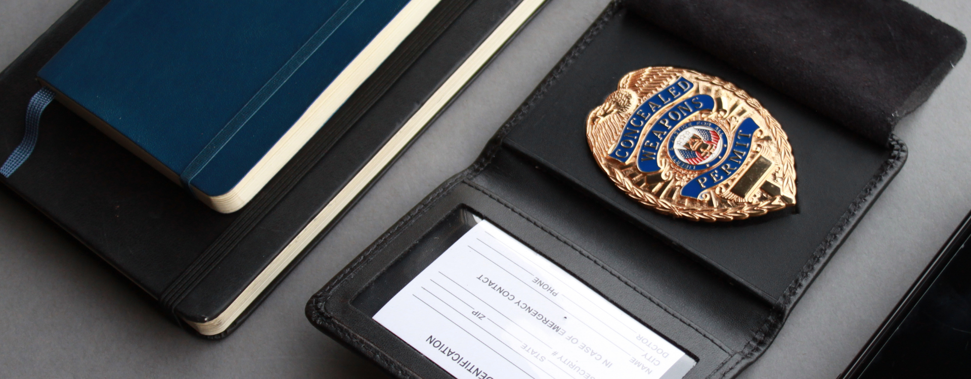 Gold police badge on a black leather badge and identification holders with a gray background