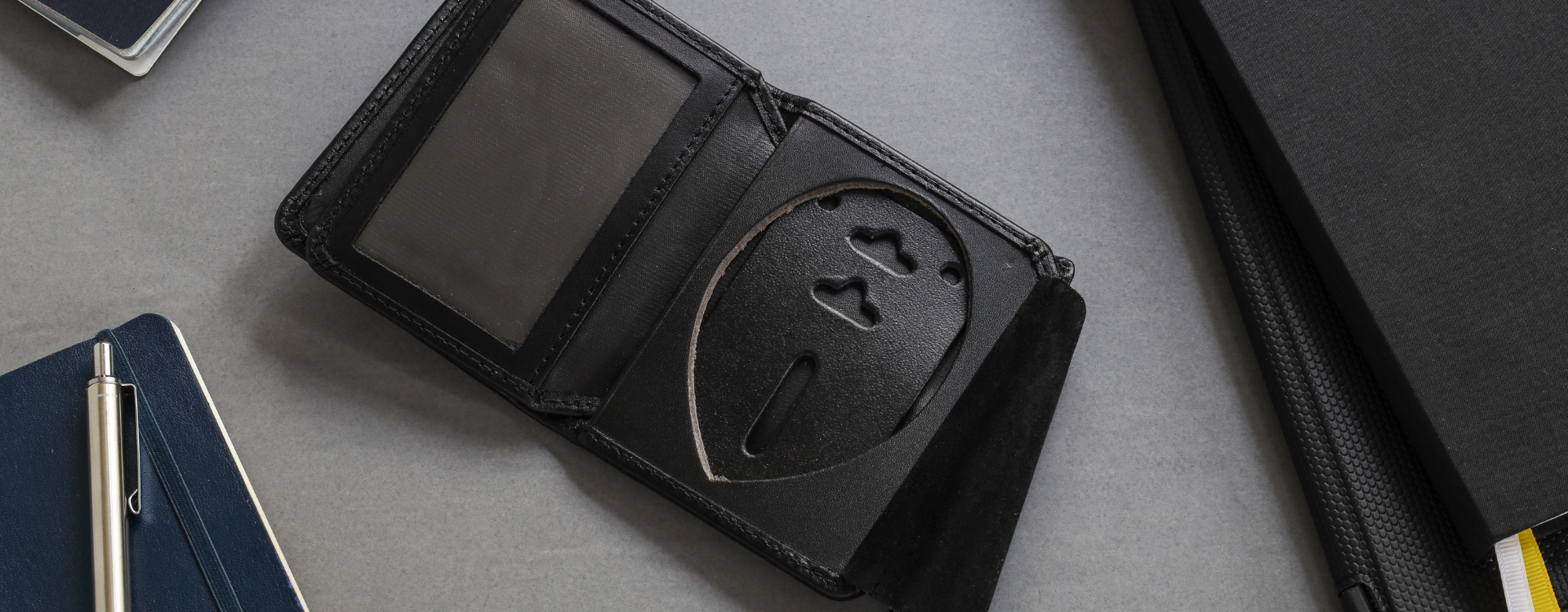 Black badge wallet with identification holder and suede badge protection flat on a gray surface