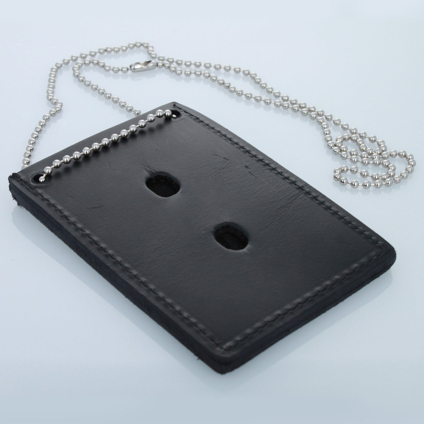 Back view of leather badge holder showing pin-mount holes.