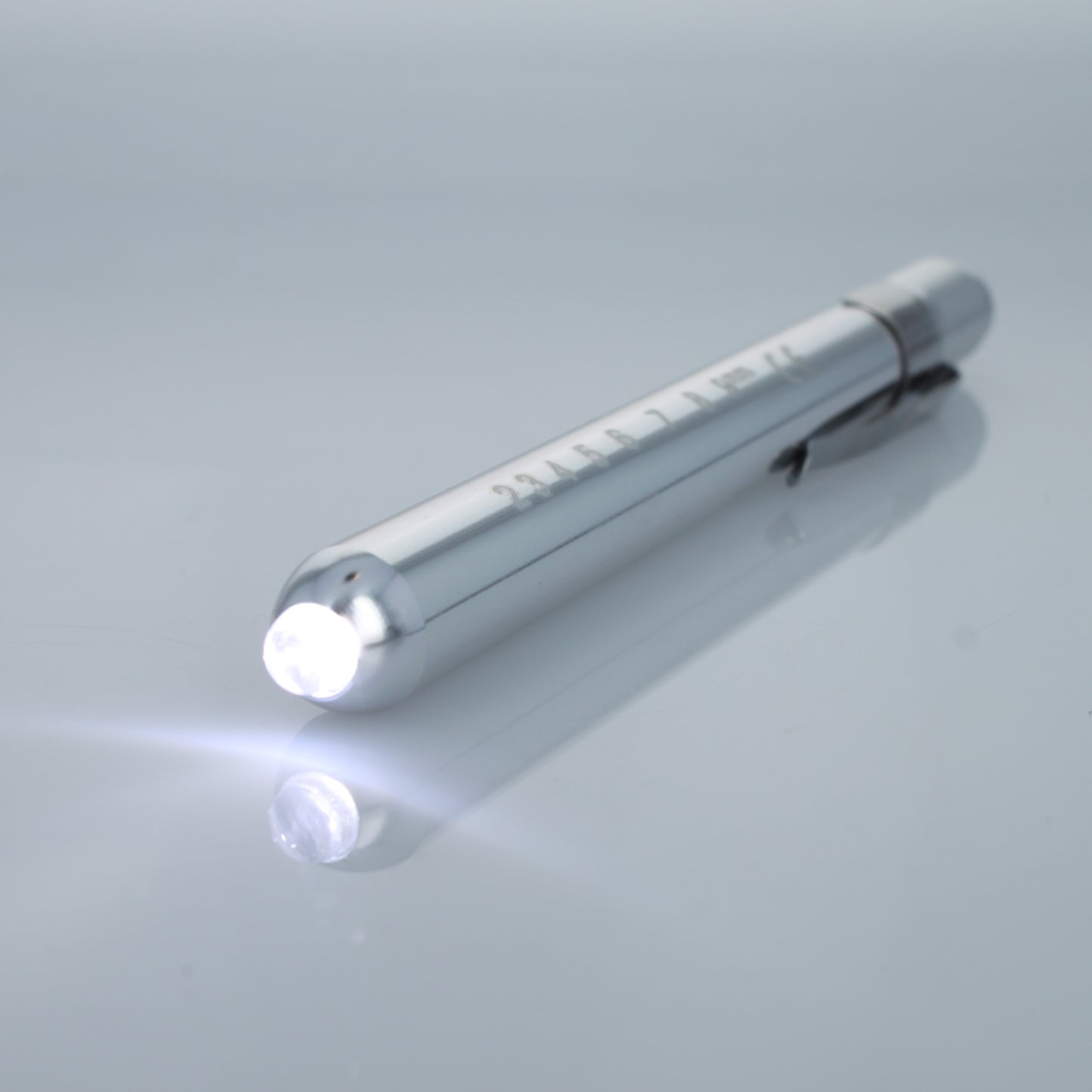 Silver EMT diagnostic pen light illuminated with bright white LED.
