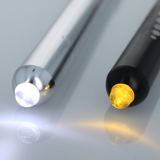 Close-up of silver and black EMT diagnostic pen lights with white and warm yellow LEDs illuminated.