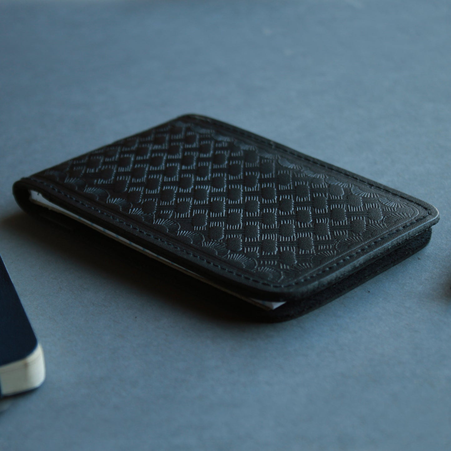 Close-up of black basketweave textured leather notepad holder.