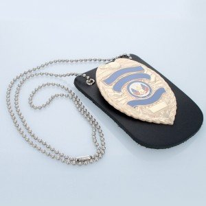 Black dog tag holder with a military-style badge on a light blue background