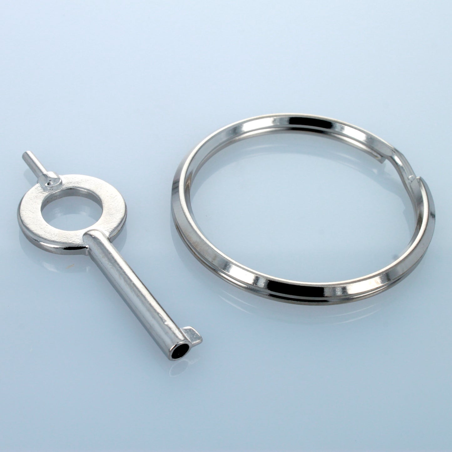 Universal handcuff key and separate keyring on reflective surface.