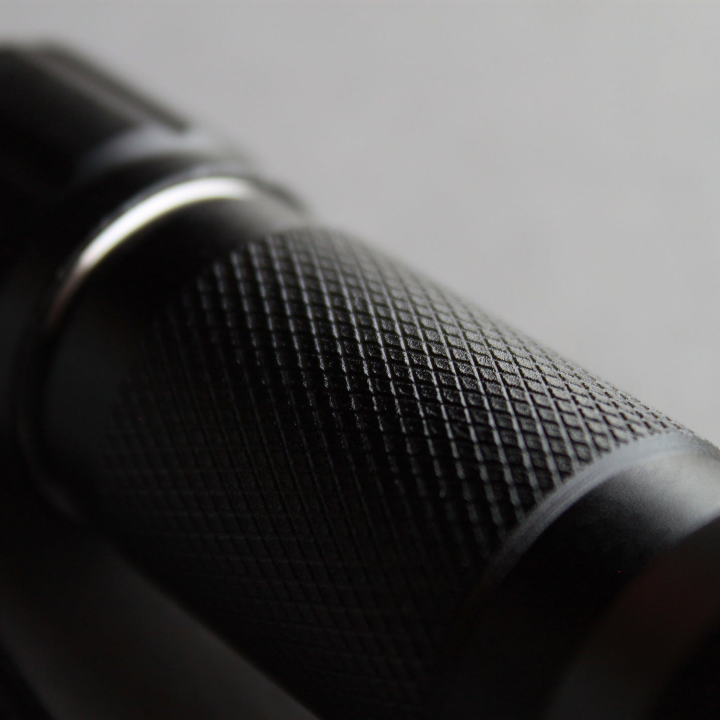 Close-up of textured anti-slip grip on black UV LED flashlight.