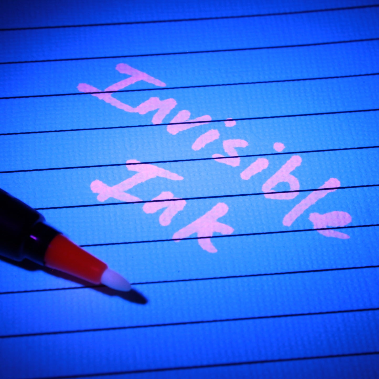 Pink UV invisible ink writing on lined paper illuminated by UV light.