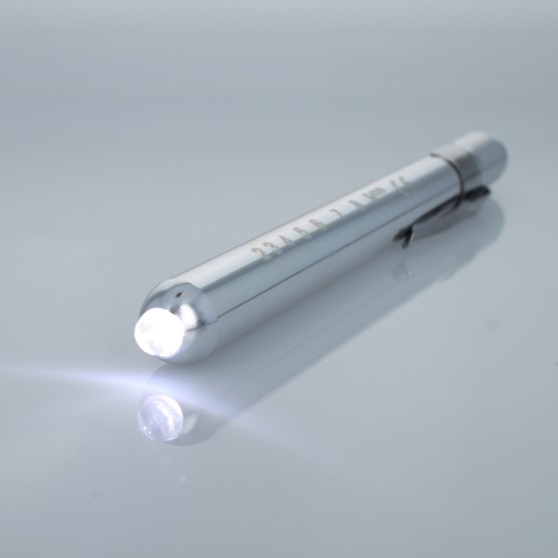 Silver EMT diagnostic pen light illuminated with bright white LED.