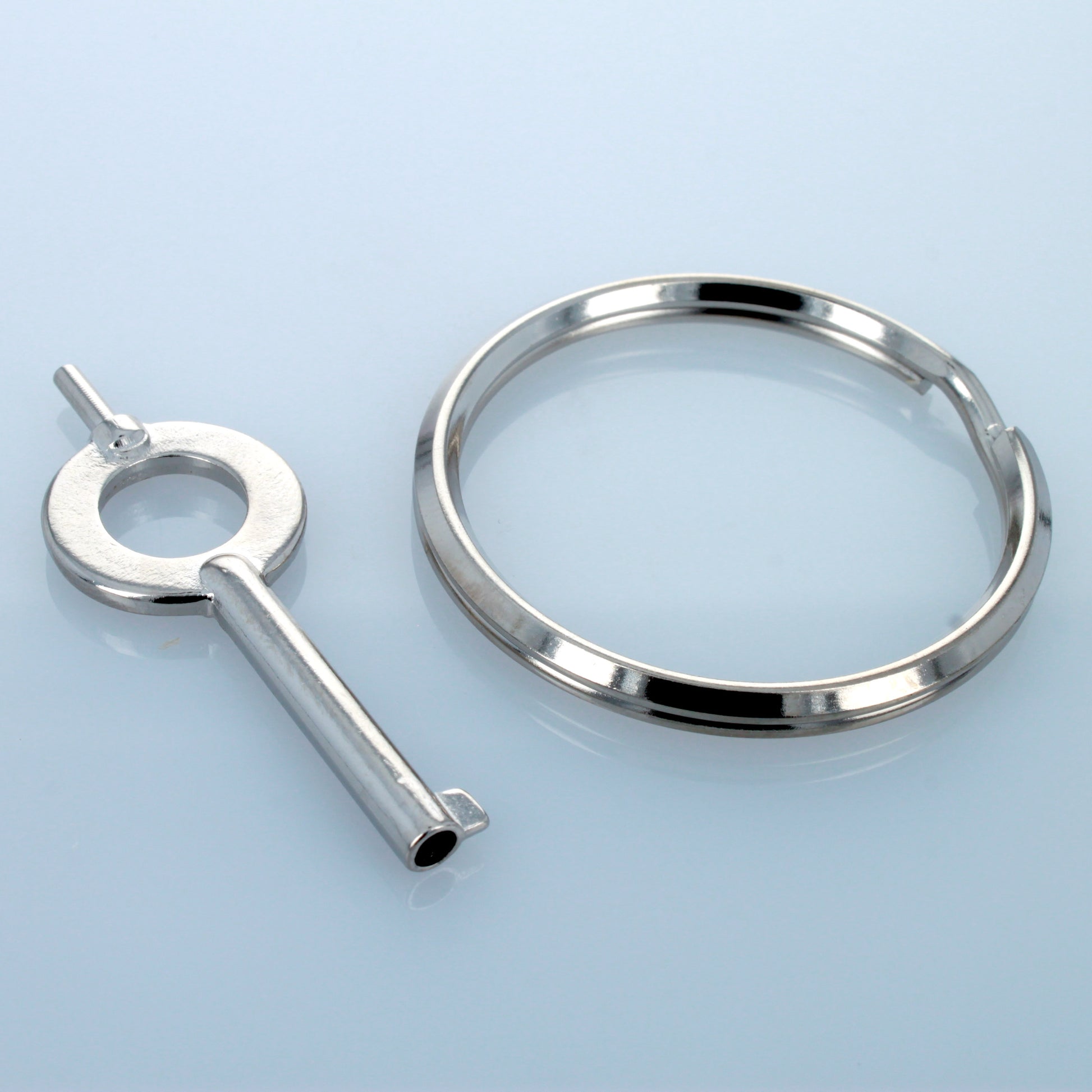 Universal handcuff key and separate keyring on reflective surface.
