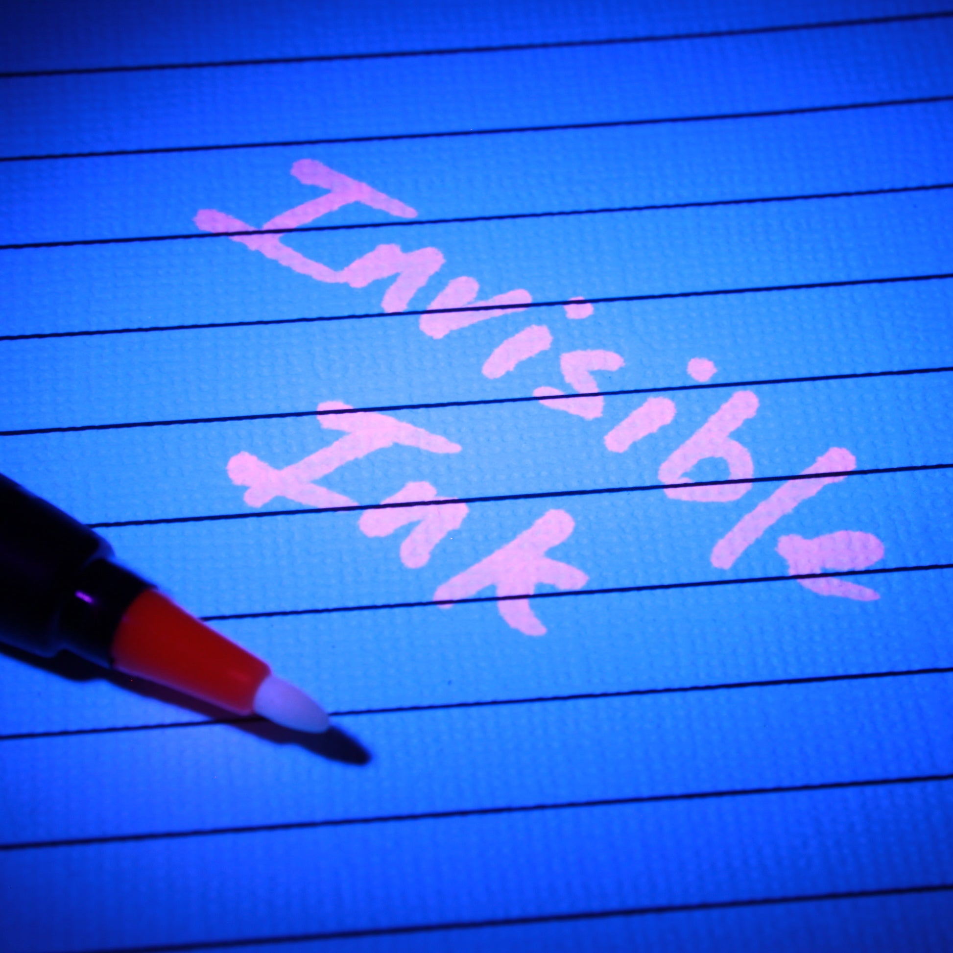 Pink UV invisible ink writing on lined paper illuminated by UV light.